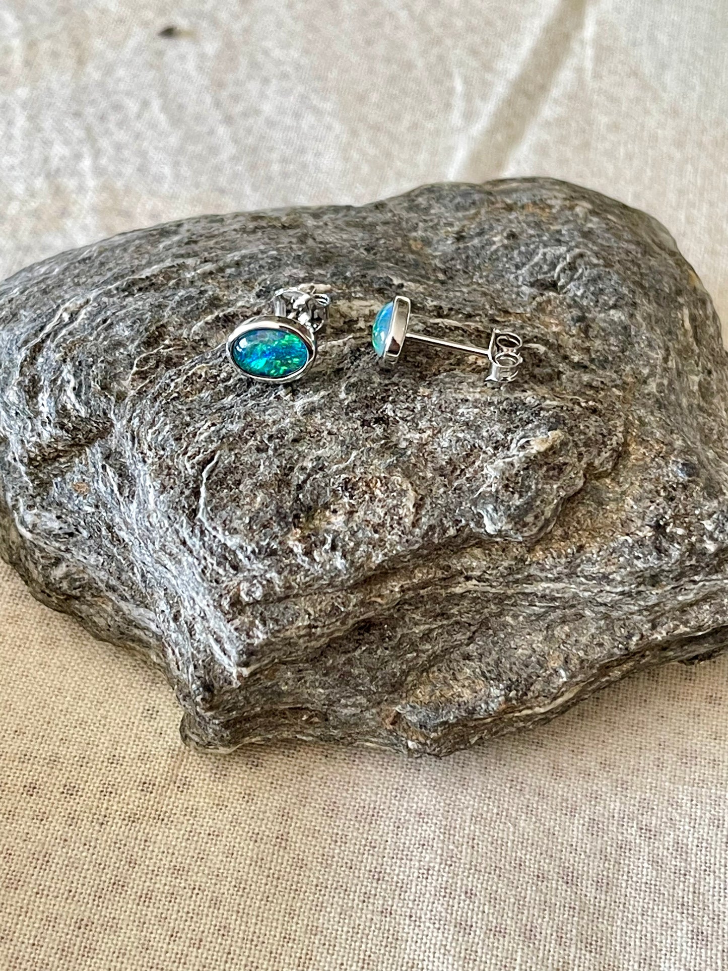 Opal earrings on a textured stone surface