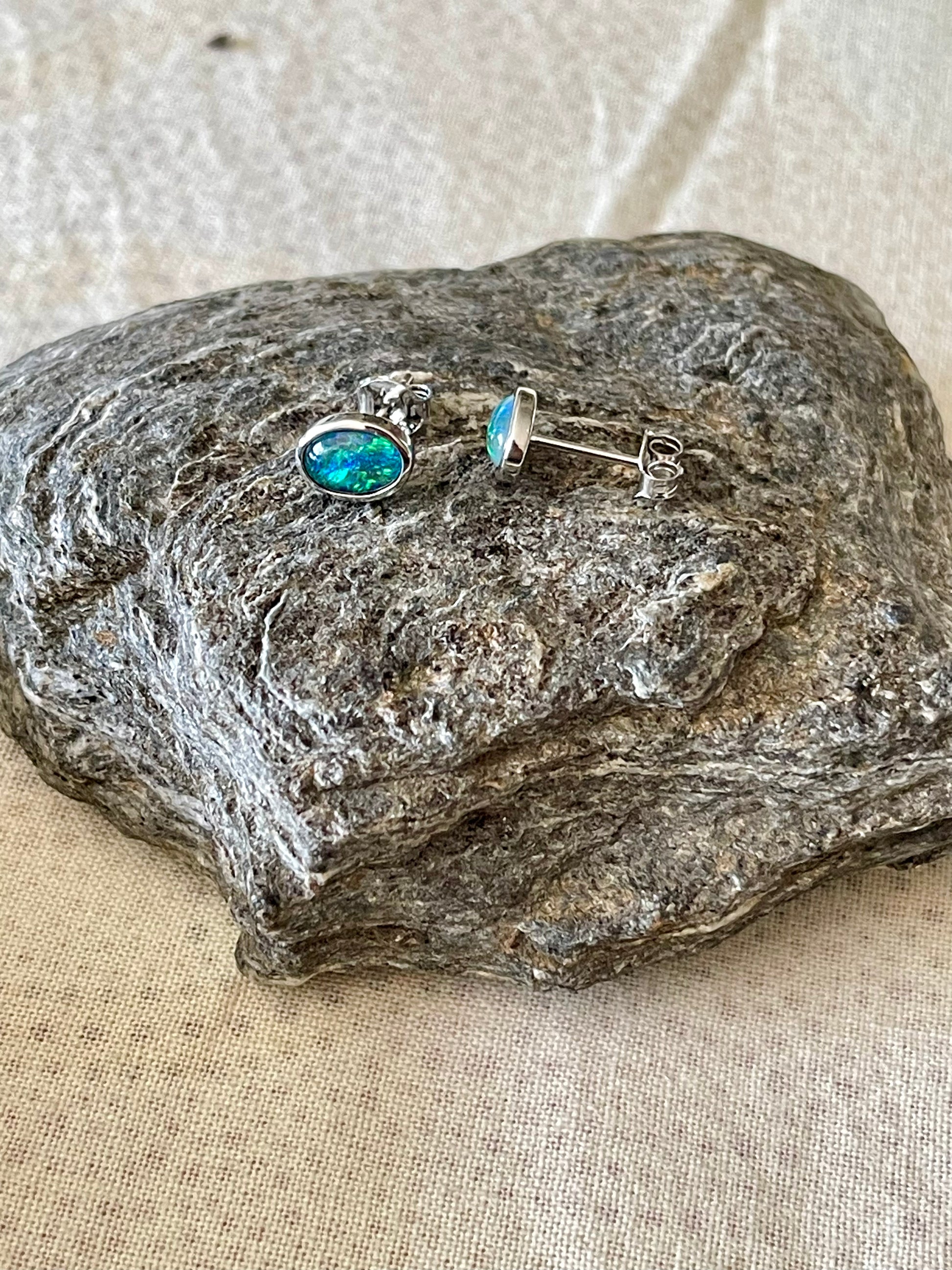 Opal earrings on a textured stone surface
