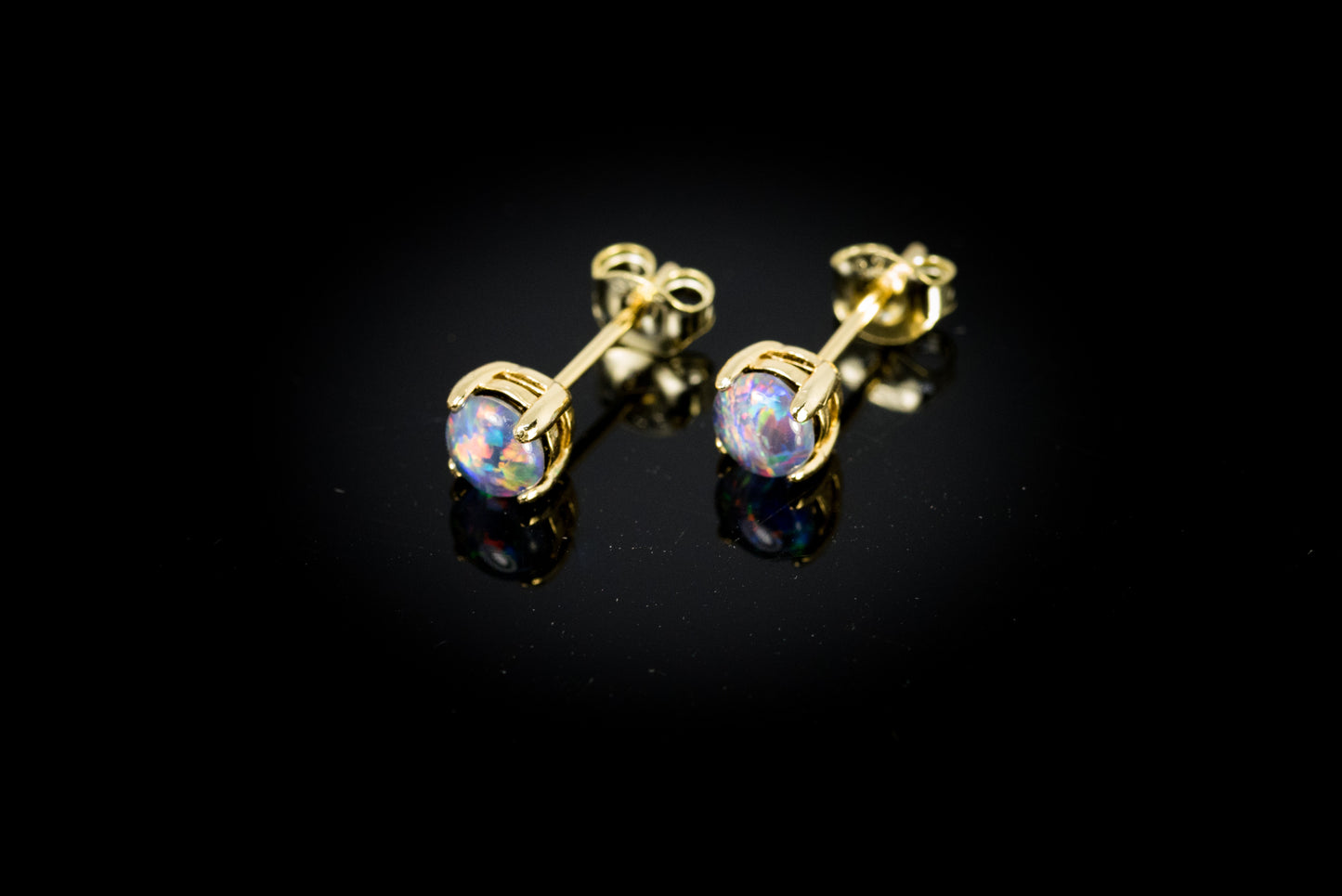 Gold earrings with opal stones on a black background