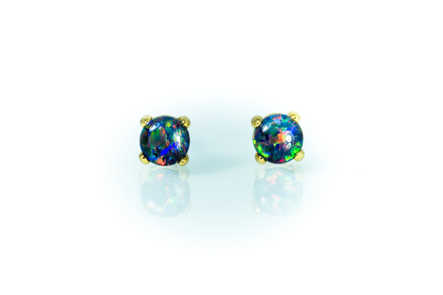 Pair of round opal earrings with gold settings on a light blue background