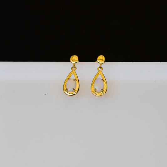 Gold teardrop opal earrings on a white background