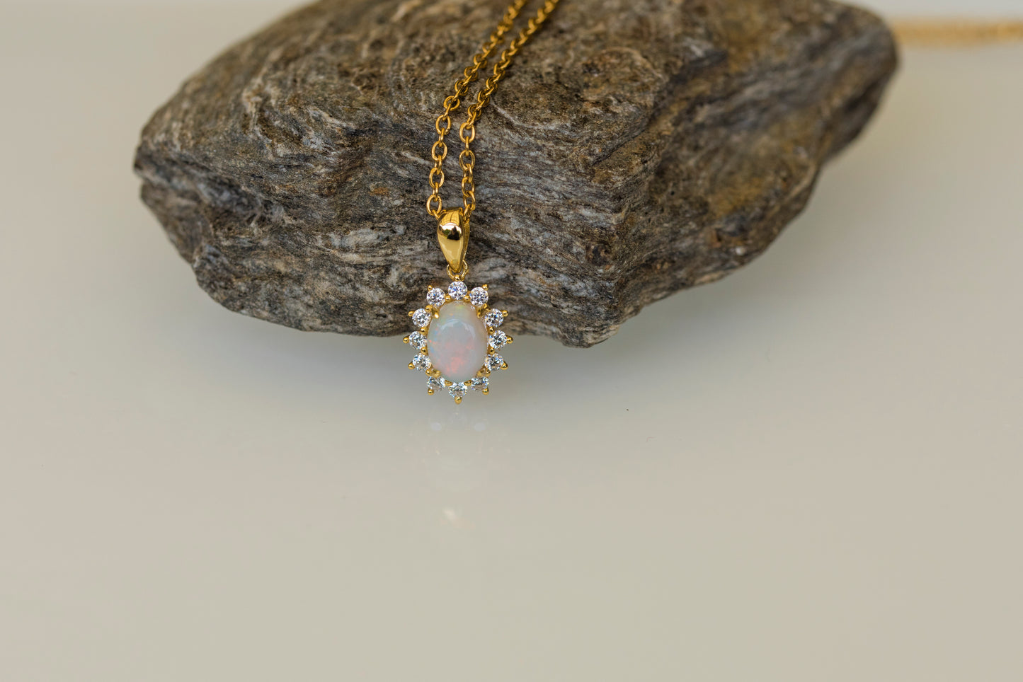 Gold opal necklace with a pendant on a rock