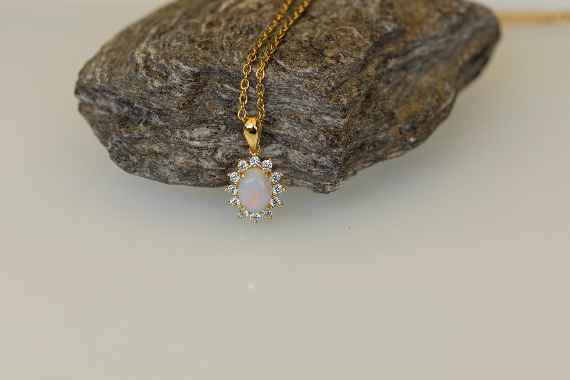Gold opal necklace with a pendant on a rock