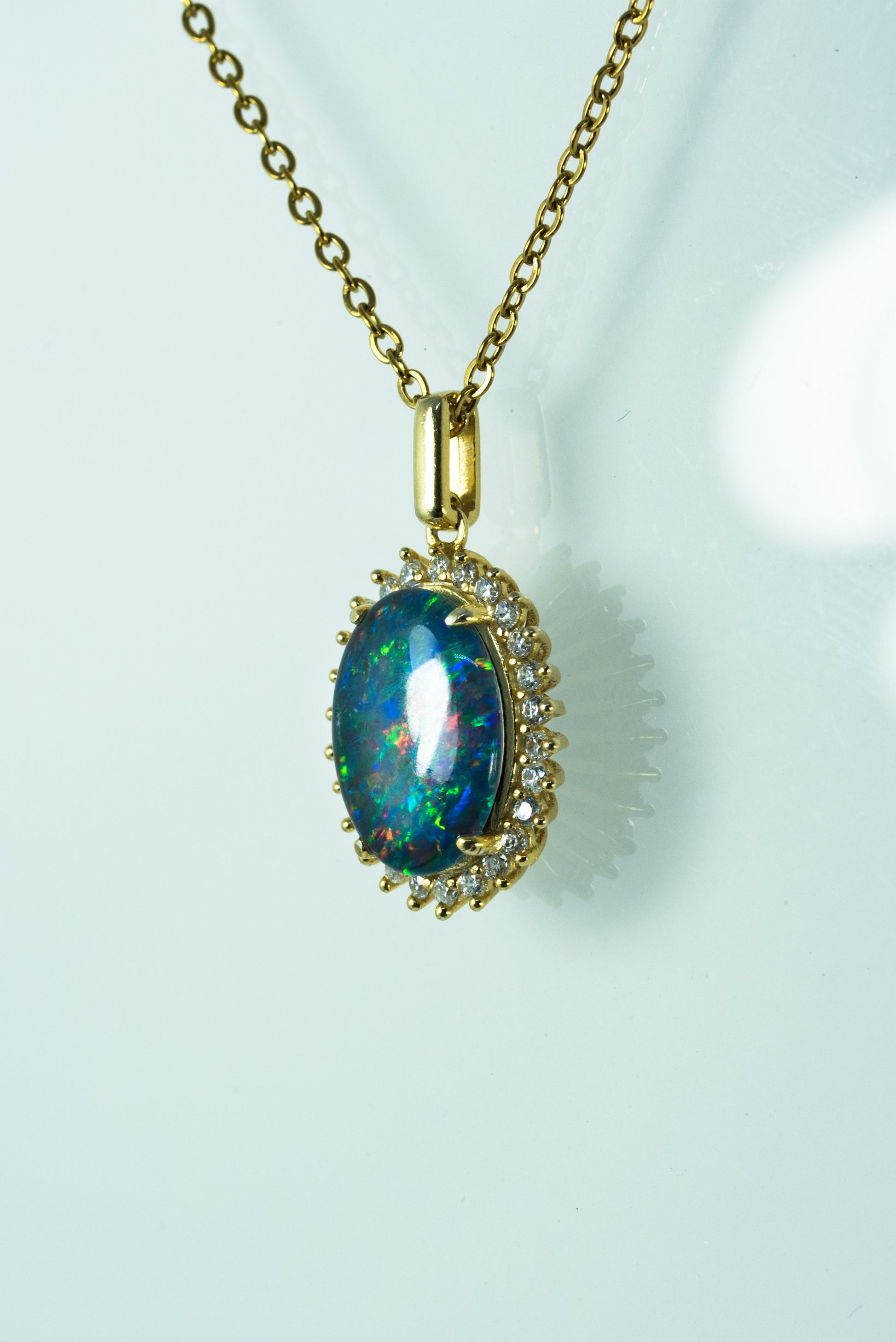 Opal pendant necklace with gold chain on a light background