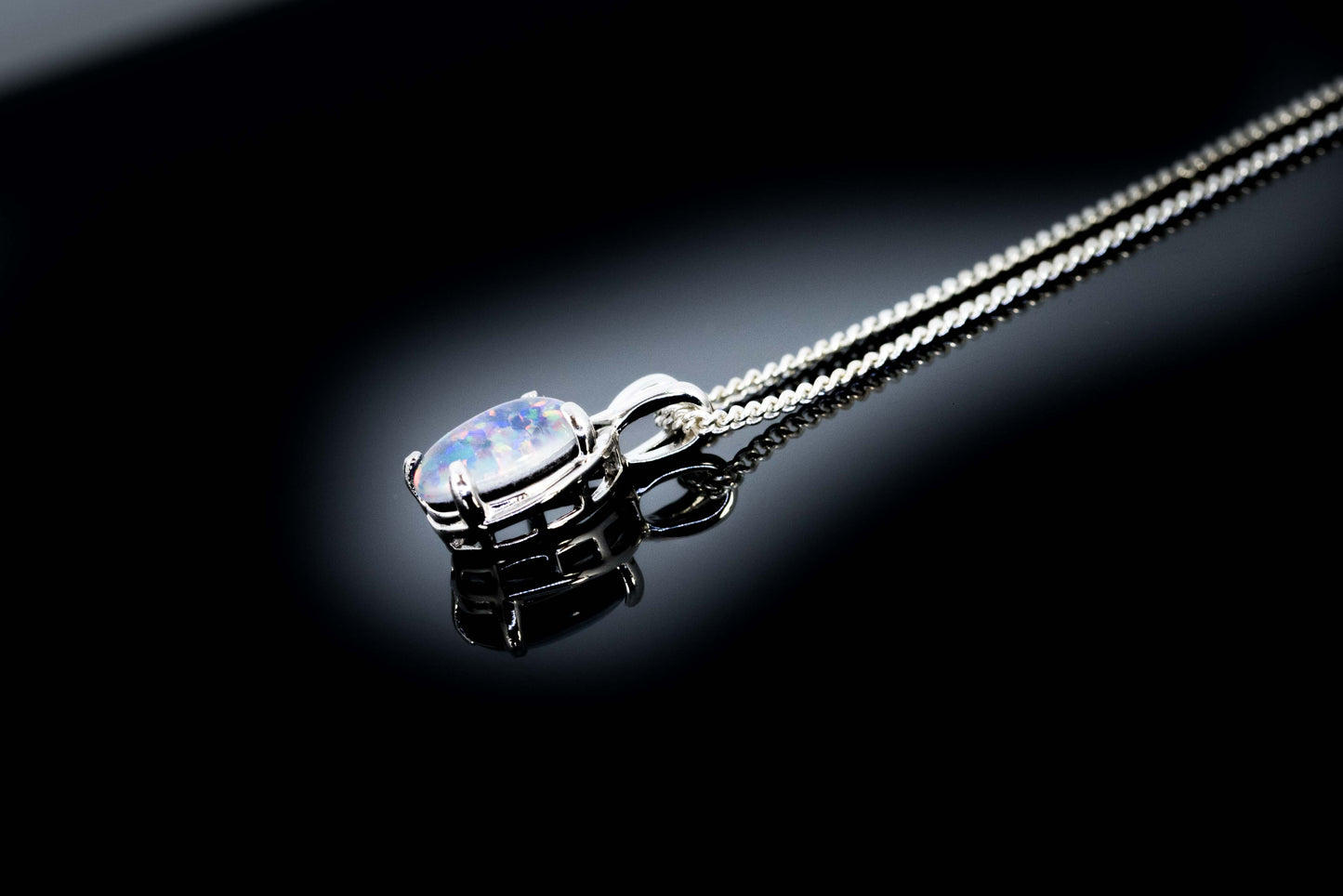 Silver necklace with an opal pendant on a black background