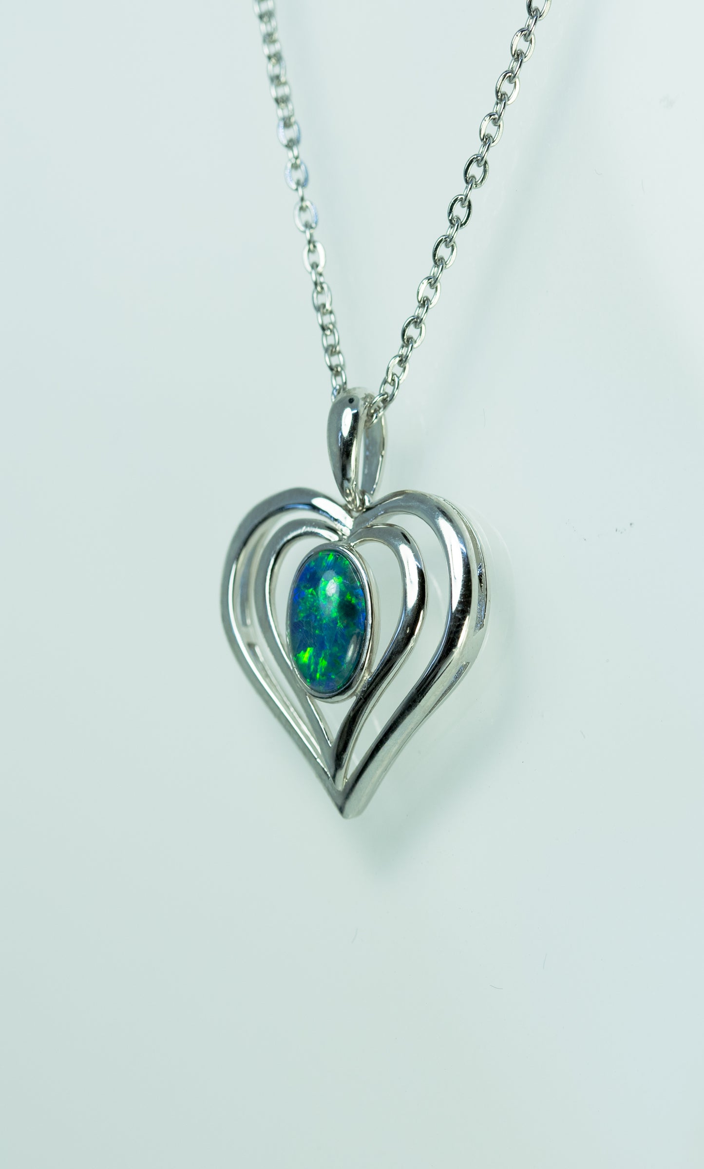 Heart-shaped pendant with a green opal gemstone on a white background
