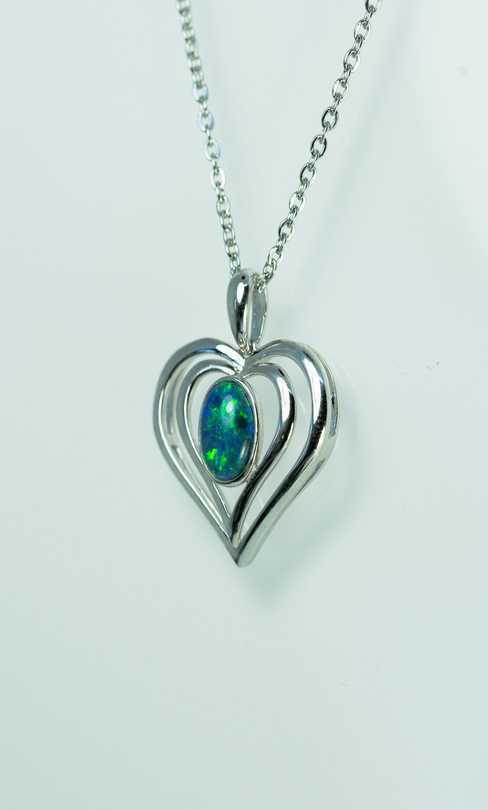 Heart-shaped pendant with a green opal gemstone on a white background