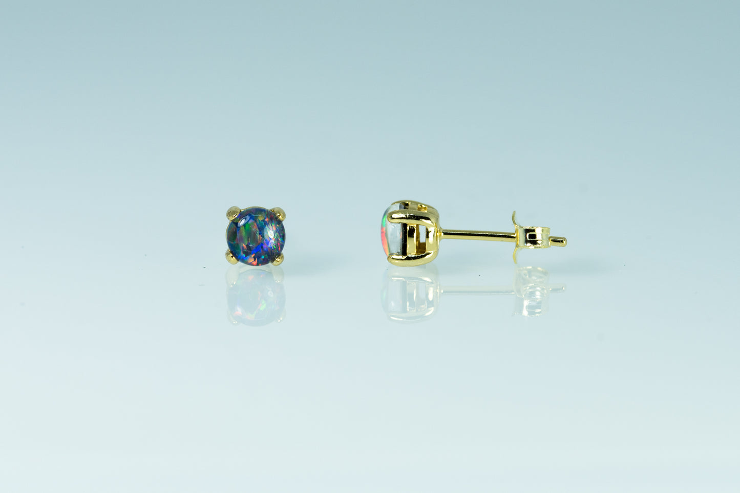 Gold earrings with opal gemstones on a light blue background
