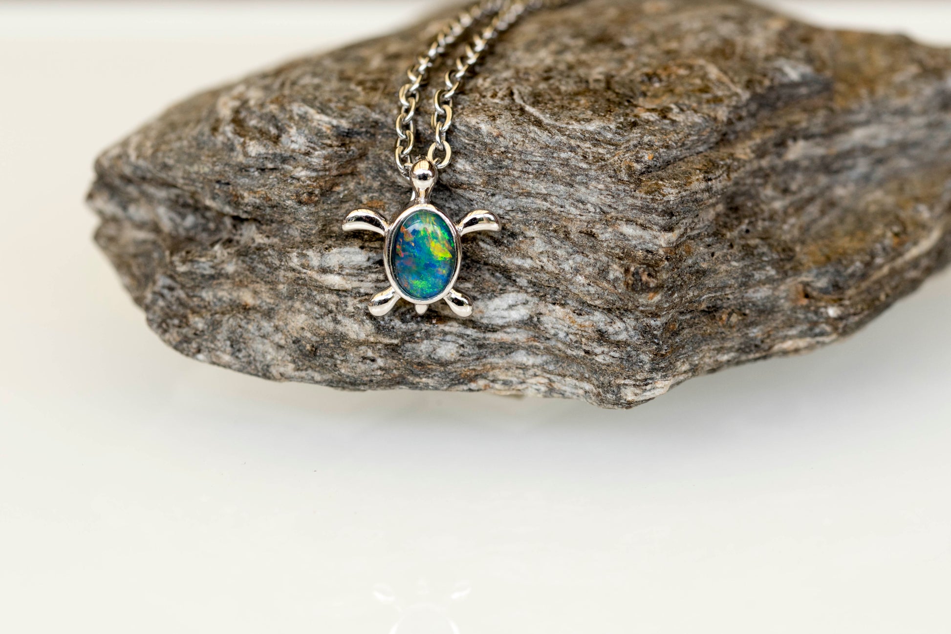 opal Necklace with a turtle-shaped pendant on a rock