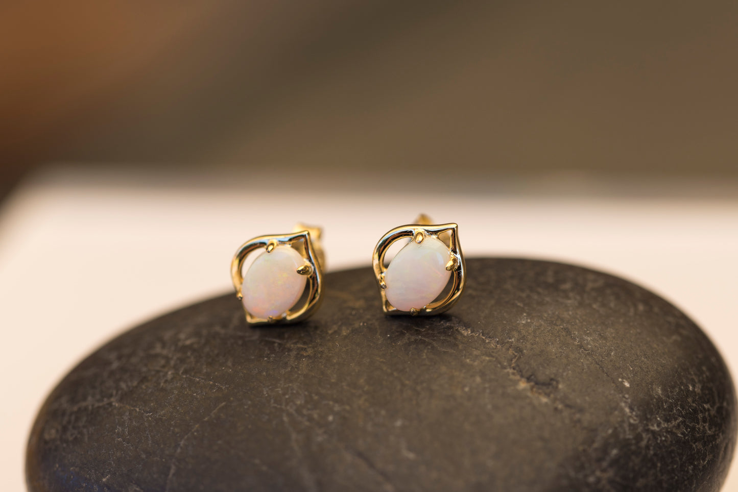 Gold opal earrings with white stones on a dark surface