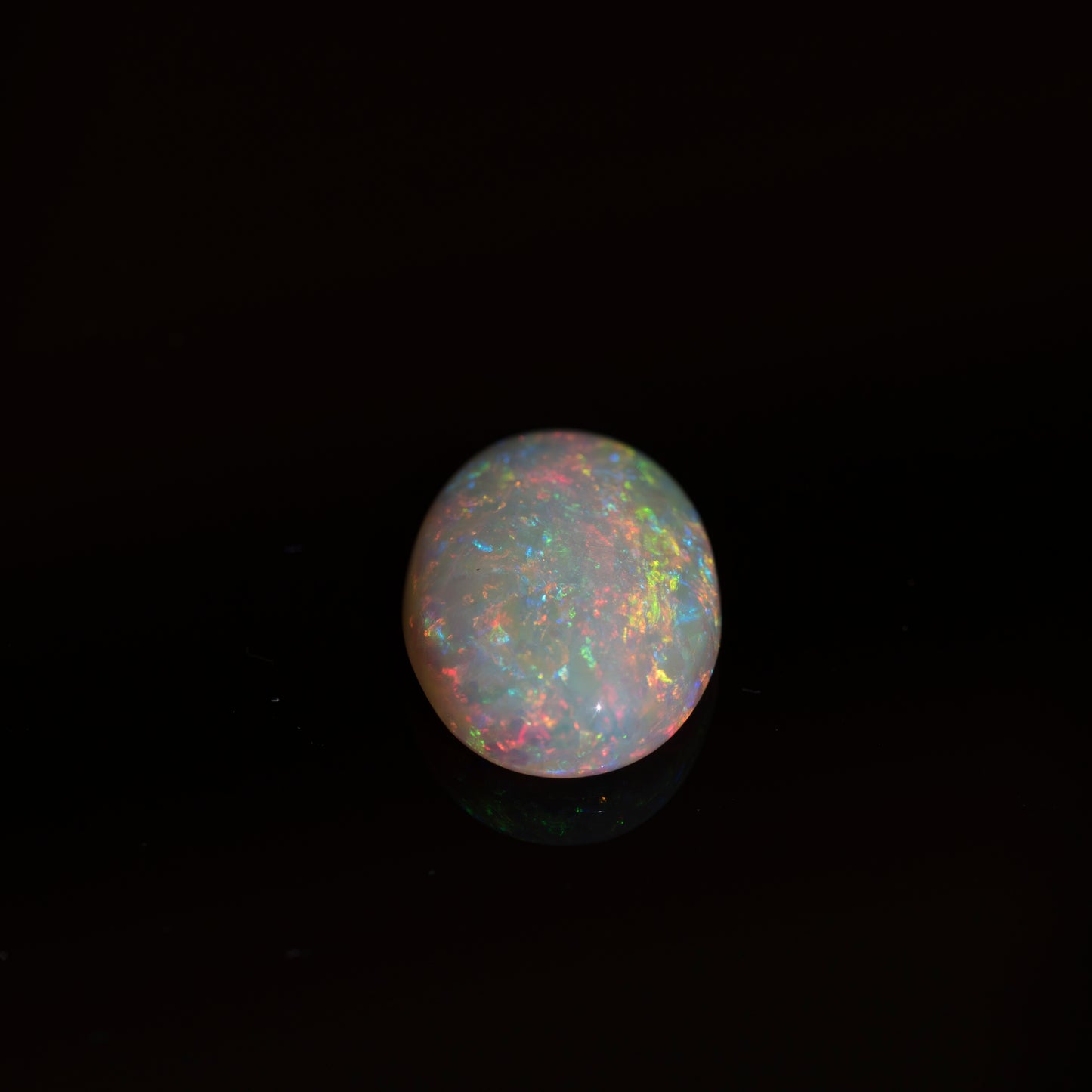 Opal gemstone with multicolored play of light on a black background