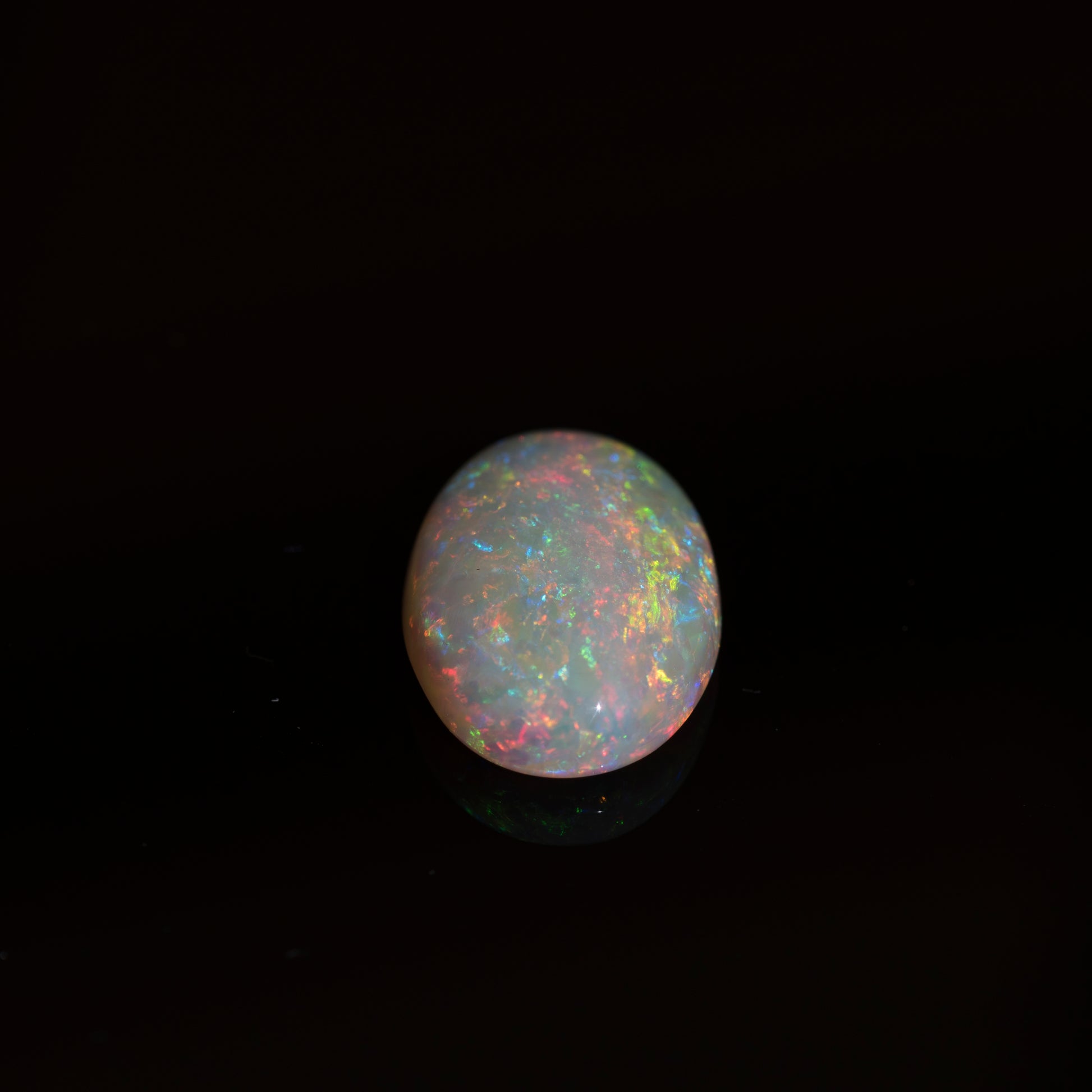 Opal gemstone with multicolored play of light on a black background