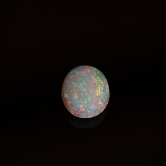 Opal gemstone with multicolored play of light on a black background