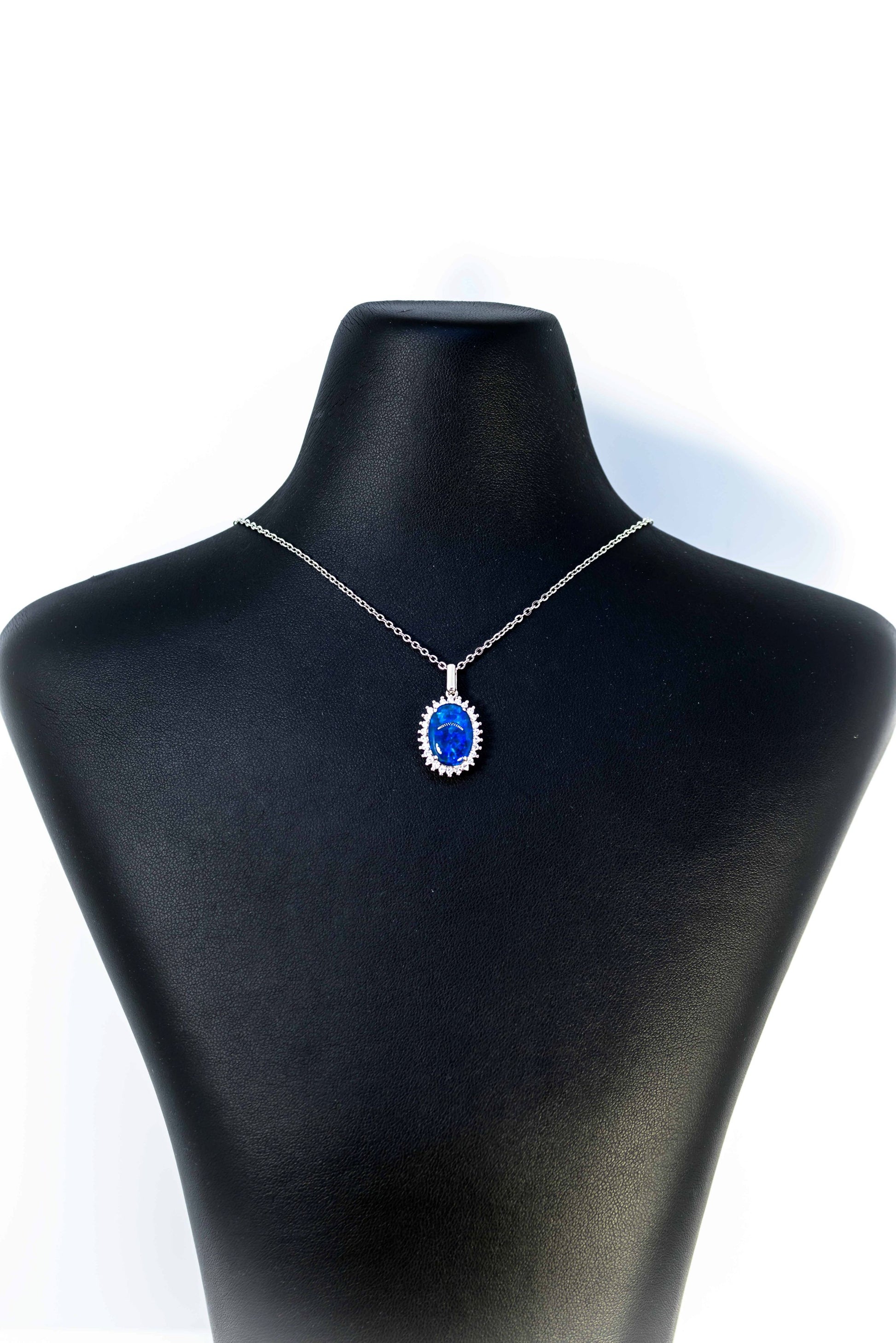 Necklace with a blue opal pendant on a black mannequin bust against a white background