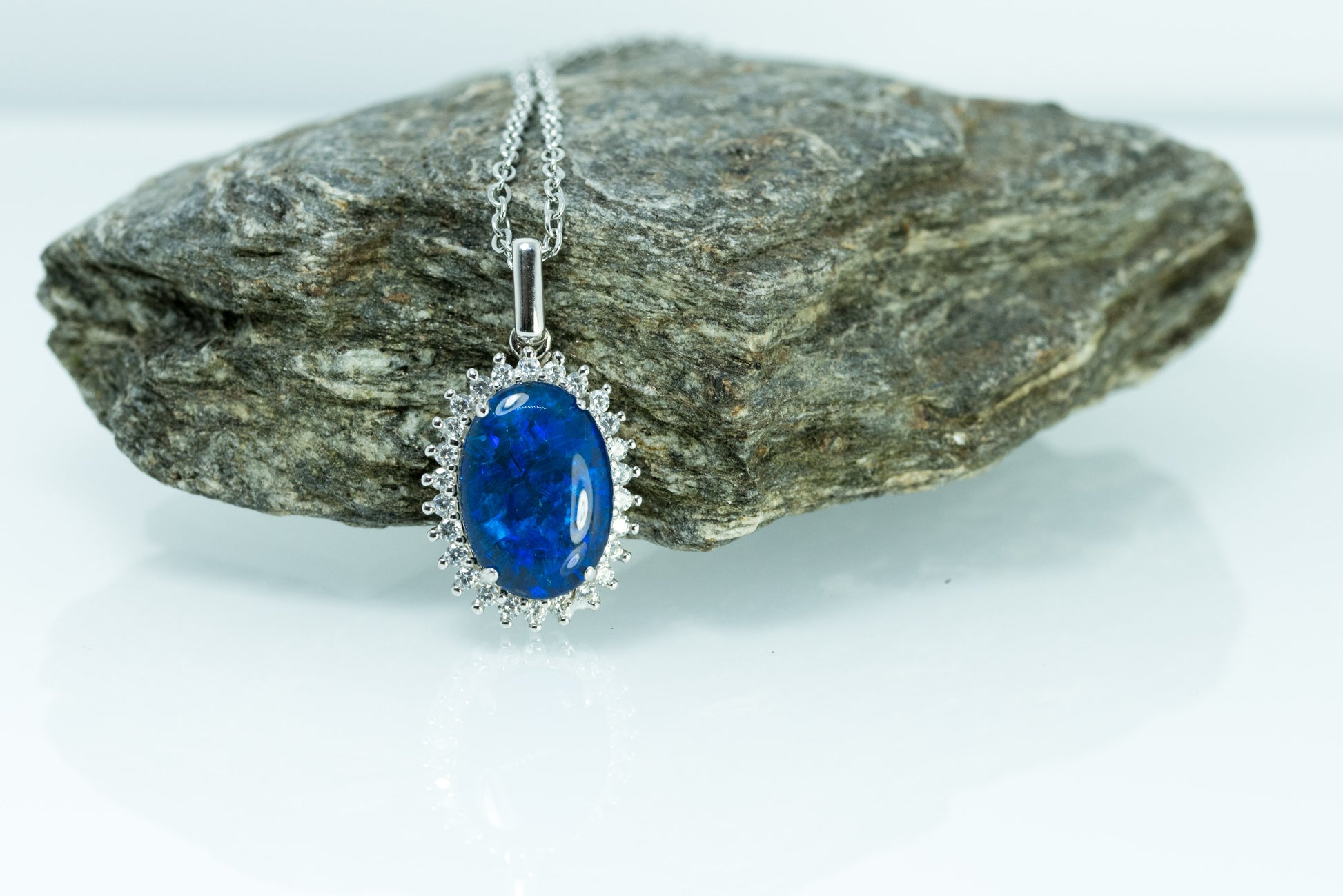 Blue Opal pendant necklace on a rock with a white background