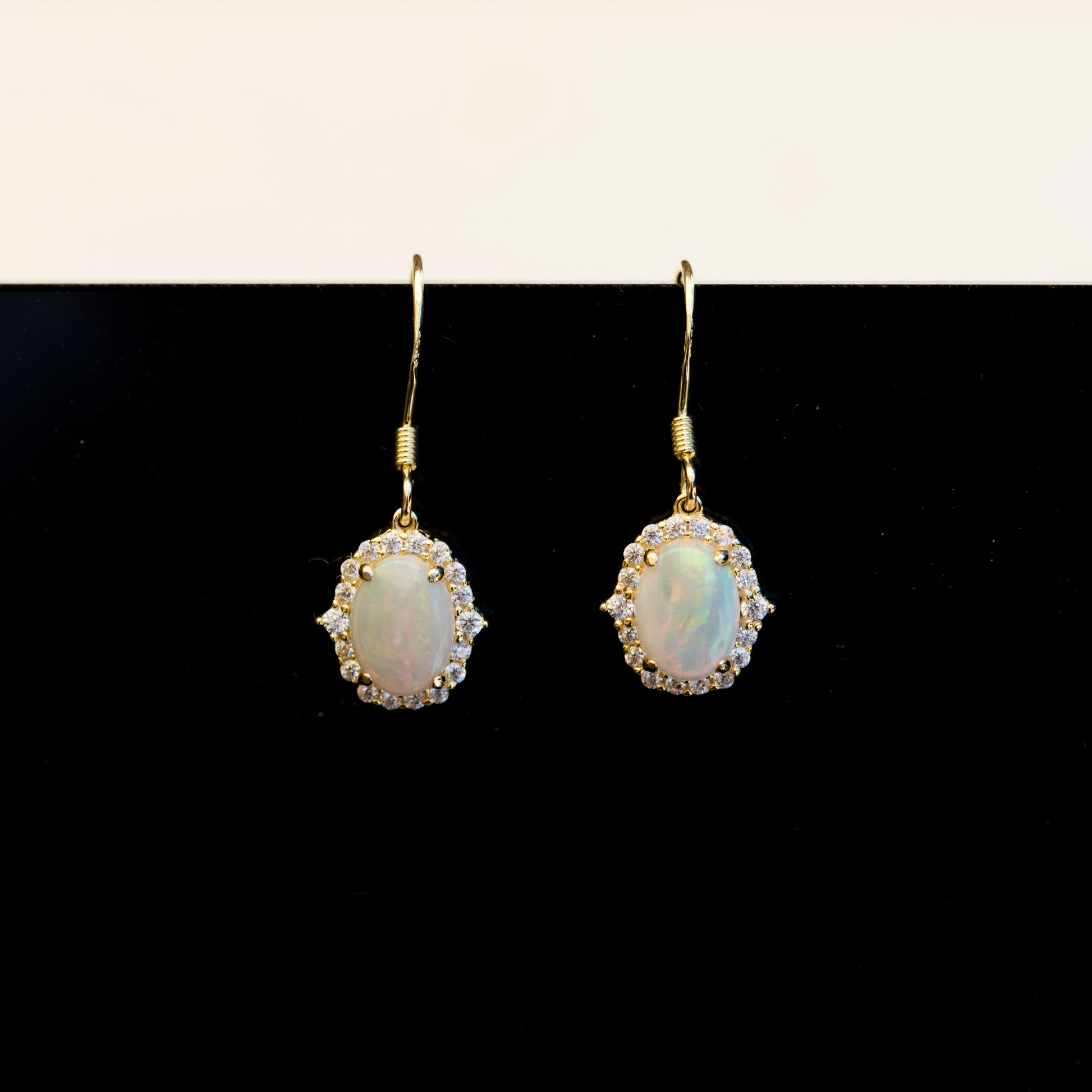 Pair of gold earrings with opal stones on a black background