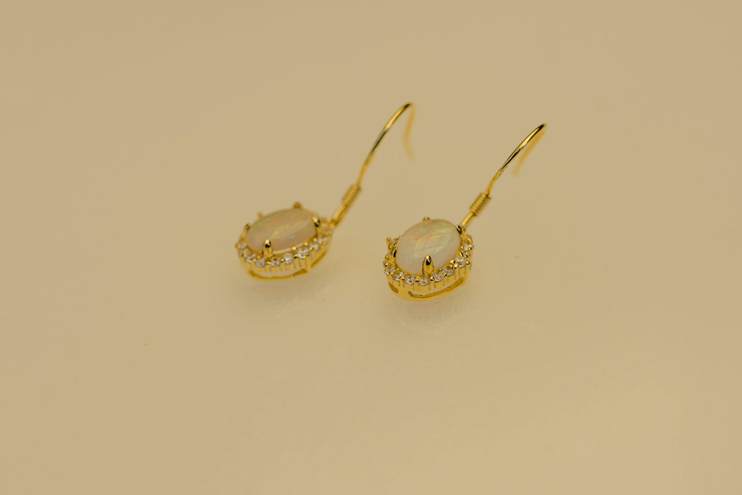 Gold earrings with gemstones on a beige background