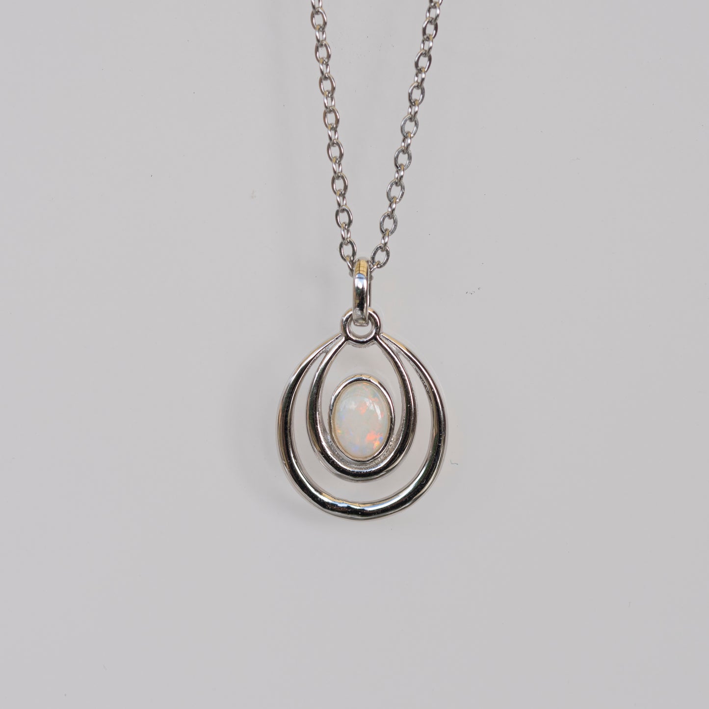 Silver pendant necklace with a light-colored gemstone on a gray background