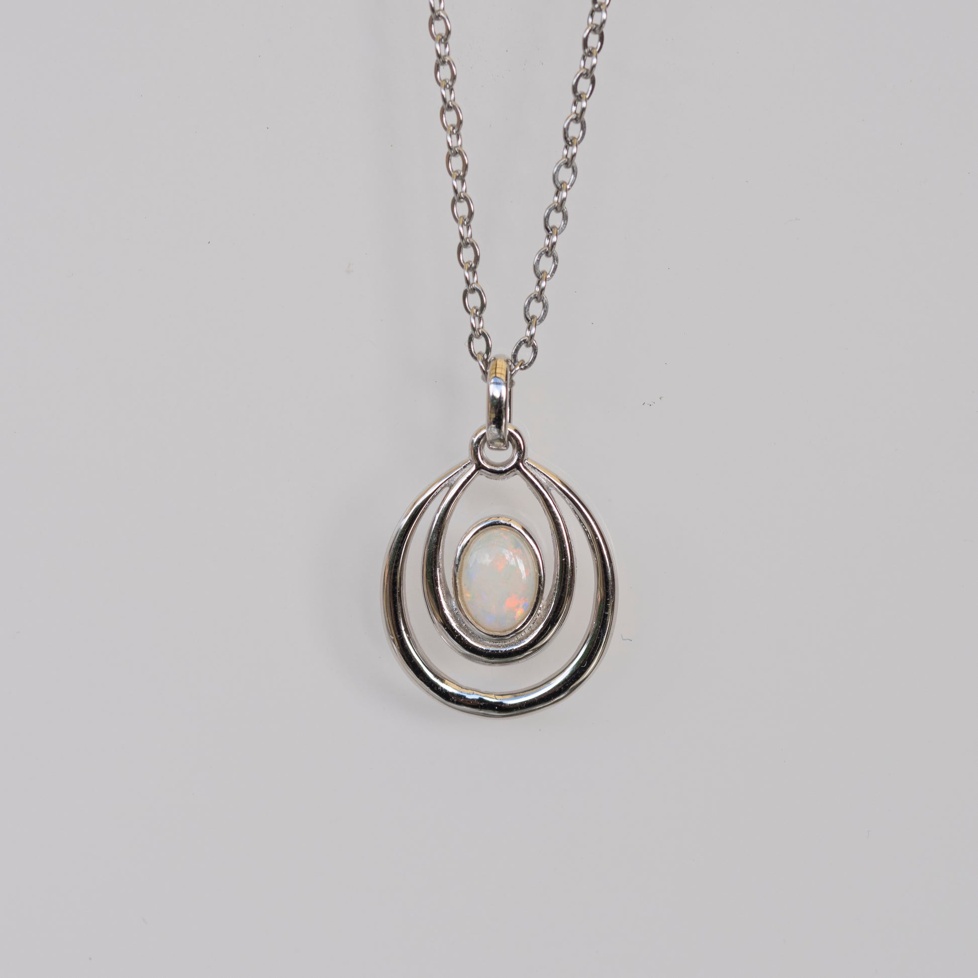 Silver pendant necklace with a light-colored gemstone on a gray background