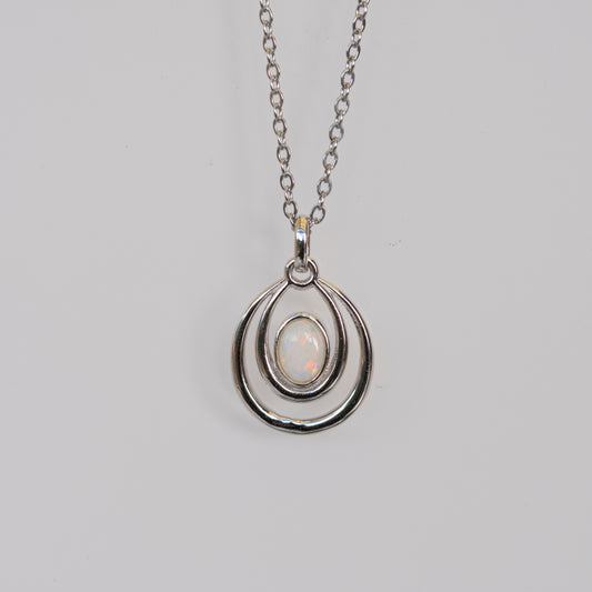 Silver pendant necklace with a light-colored gemstone on a gray background