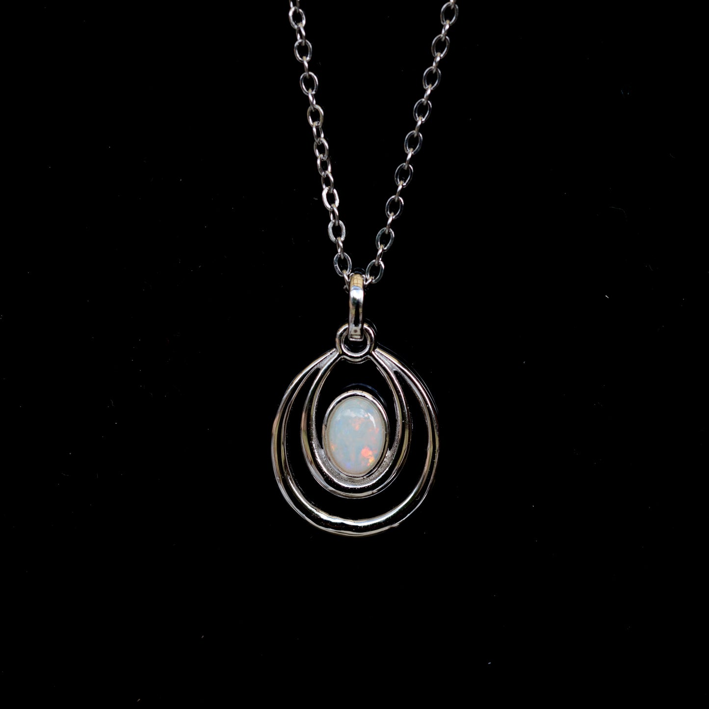 Silver necklace with a pendant featuring an opal stone on a black background
