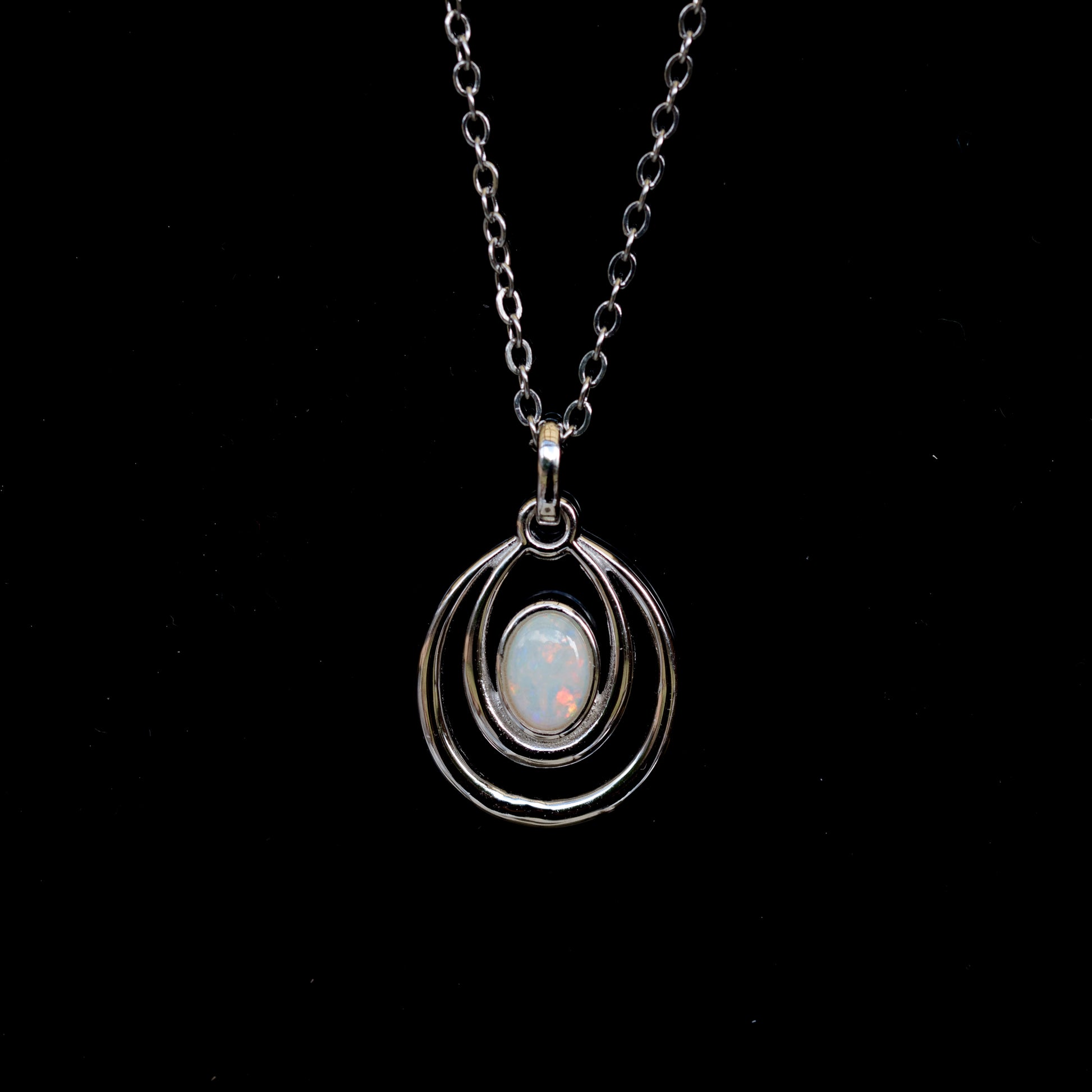 Silver necklace with a pendant featuring an opal stone on a black background