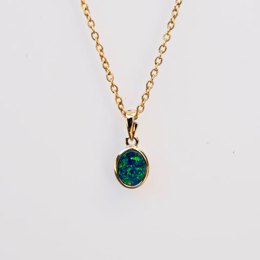 Gold necklace with a green opal pendant on a white background