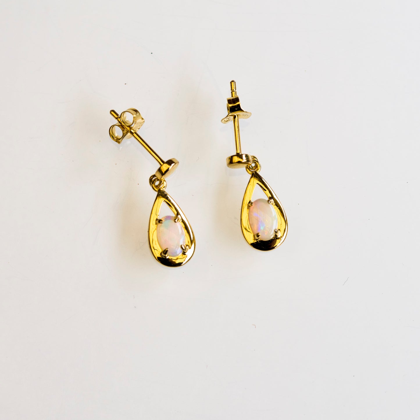 Gold teardrop earrings with opal stones on a white background