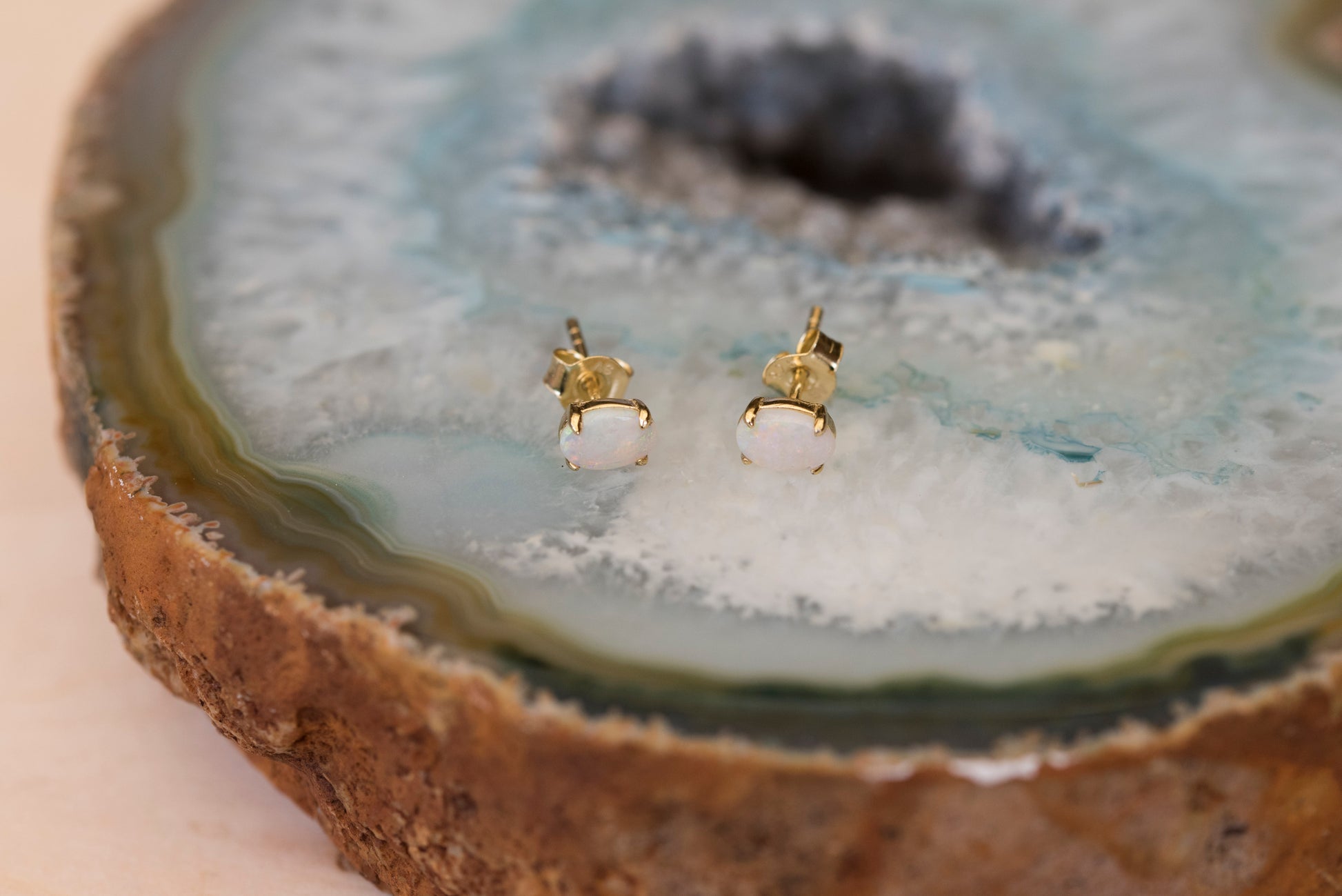 Gold opal earrings on a natural stone surface