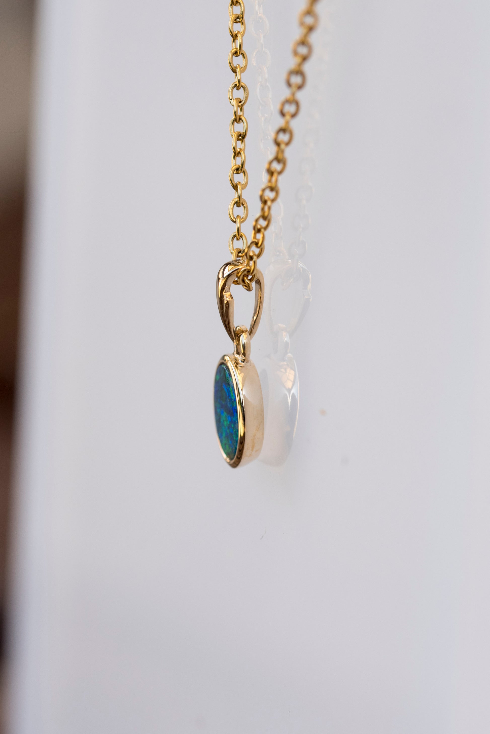 Gold opal necklace with a blue pendant on a white background