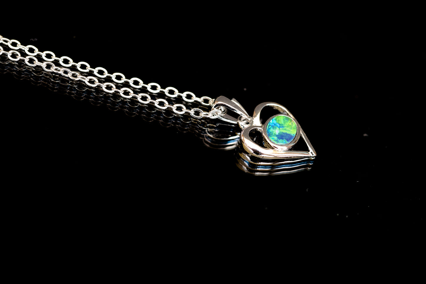 gold necklace with a heart-shaped opal pendant on a black background