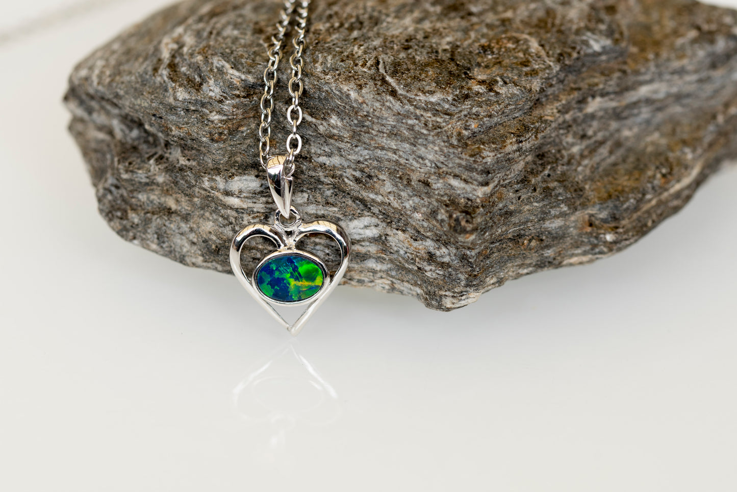 Heart-shaped opal necklace with a world map pendant on a rock