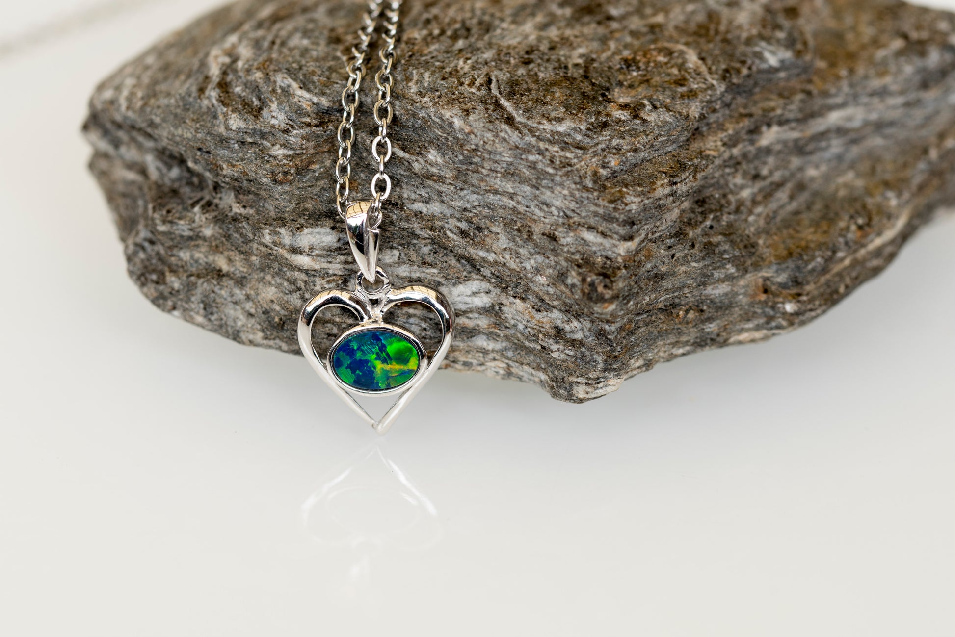Heart-shaped opal necklace with a world map pendant on a rock