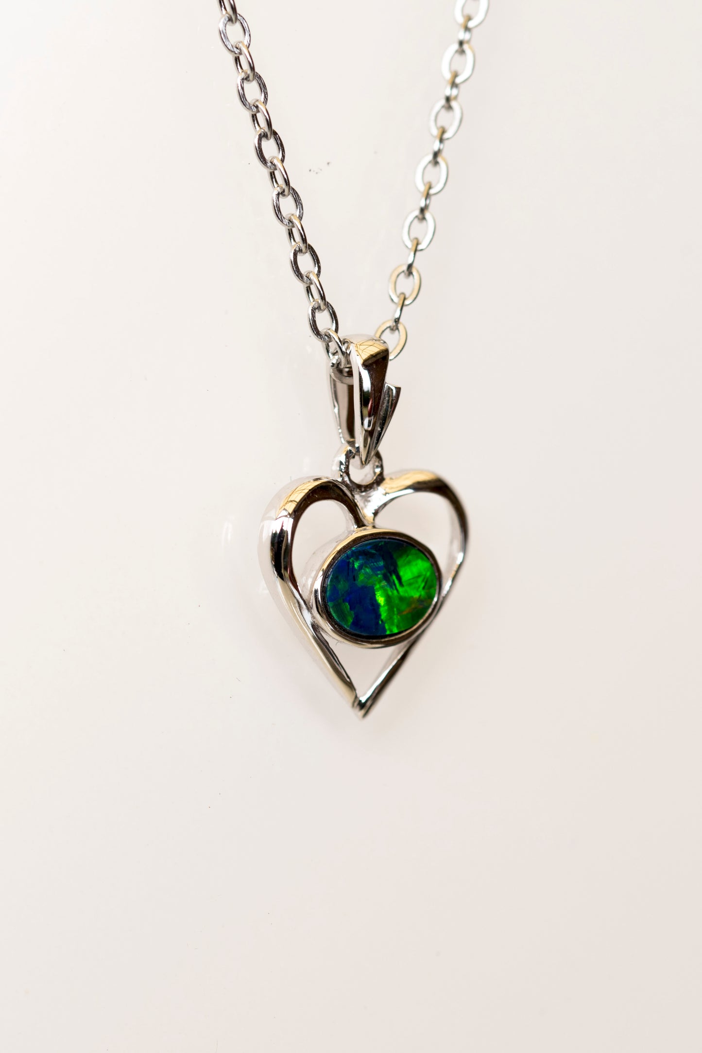 Heart-shaped pendant with a green opal gemstone on a white background