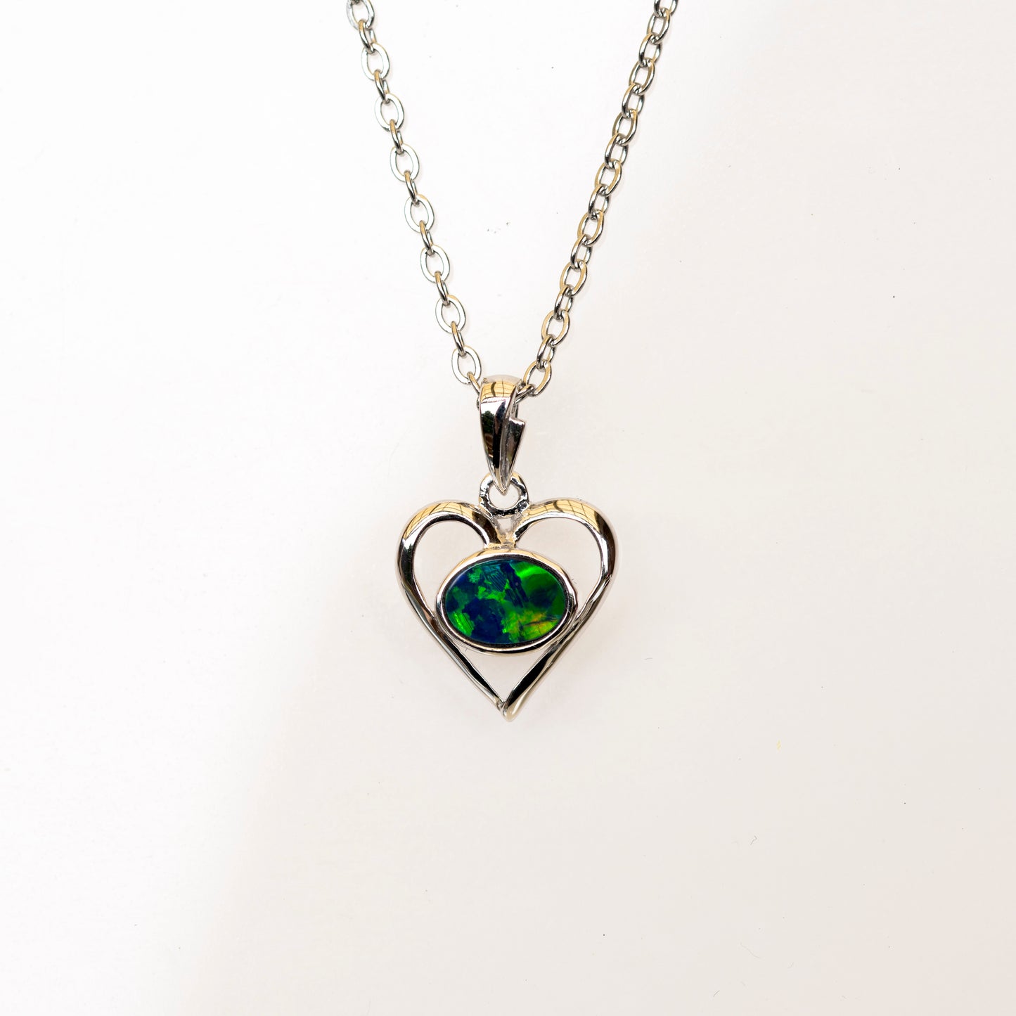 Heart-shaped pendant with green opal gemstone on a white background