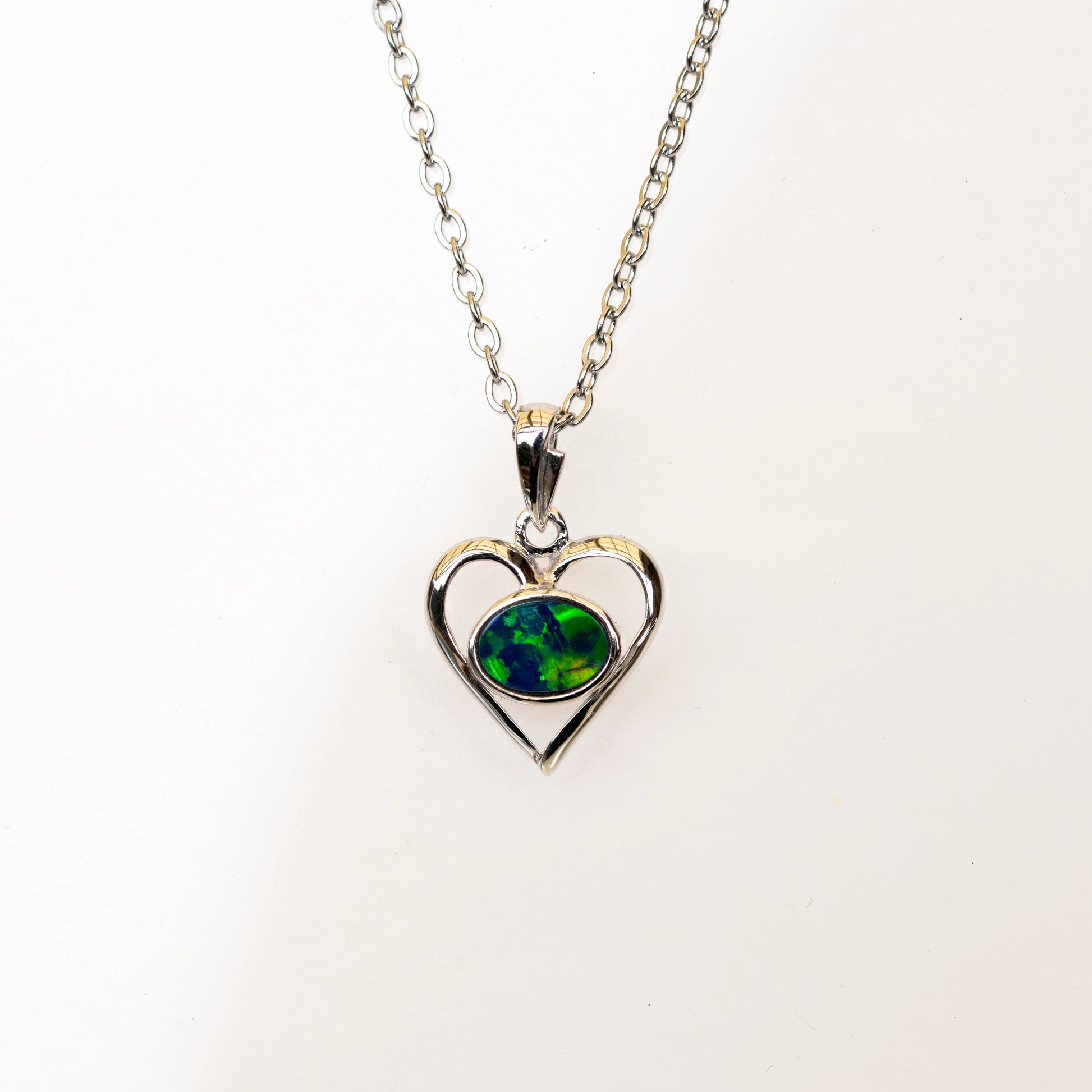 Heart-shaped pendant with green opal gemstone on a white background