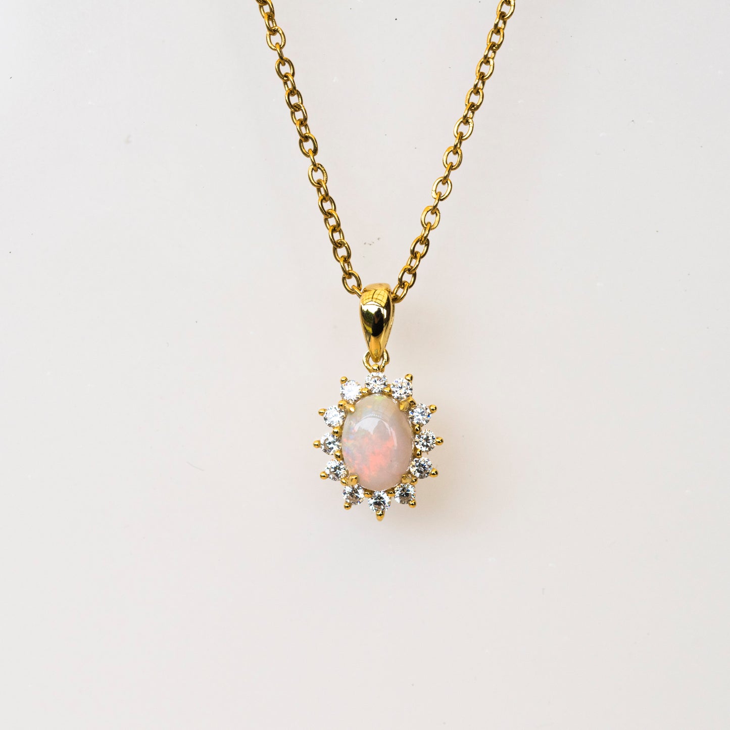 Gold necklace with a pendant featuring an opal stone on a white background