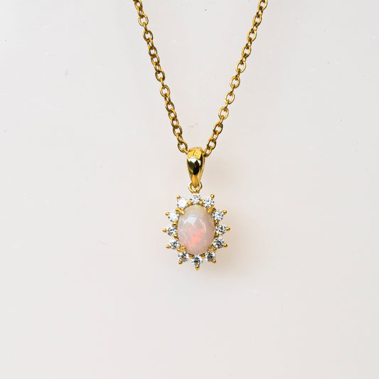 Gold necklace with a pendant featuring an opal stone on a white background