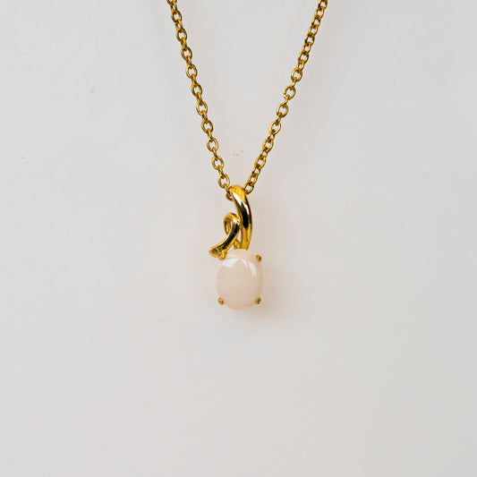 Gold necklace with a natural opal pendant on a light gray background
