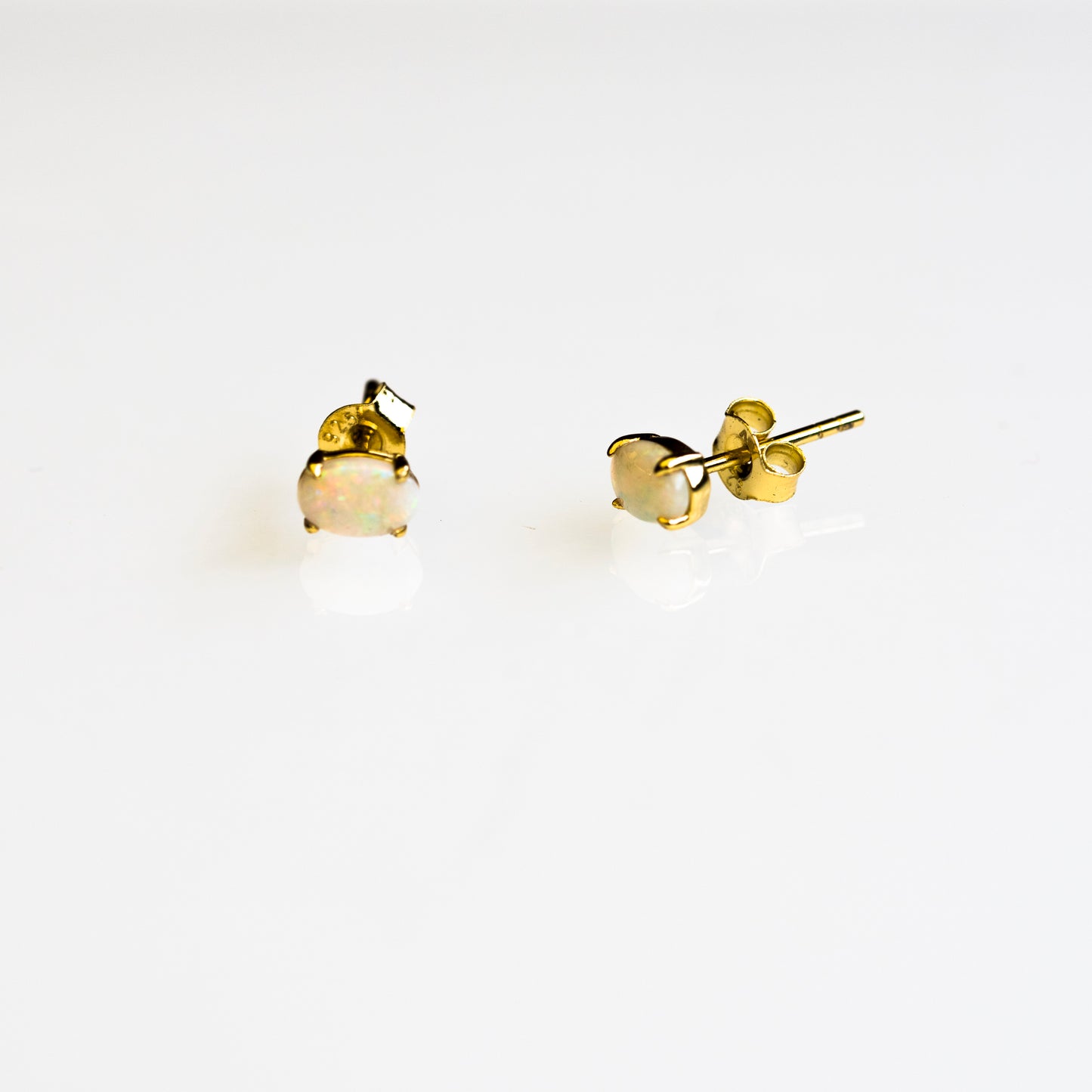 Gold Australian opal stud earrings on a white background