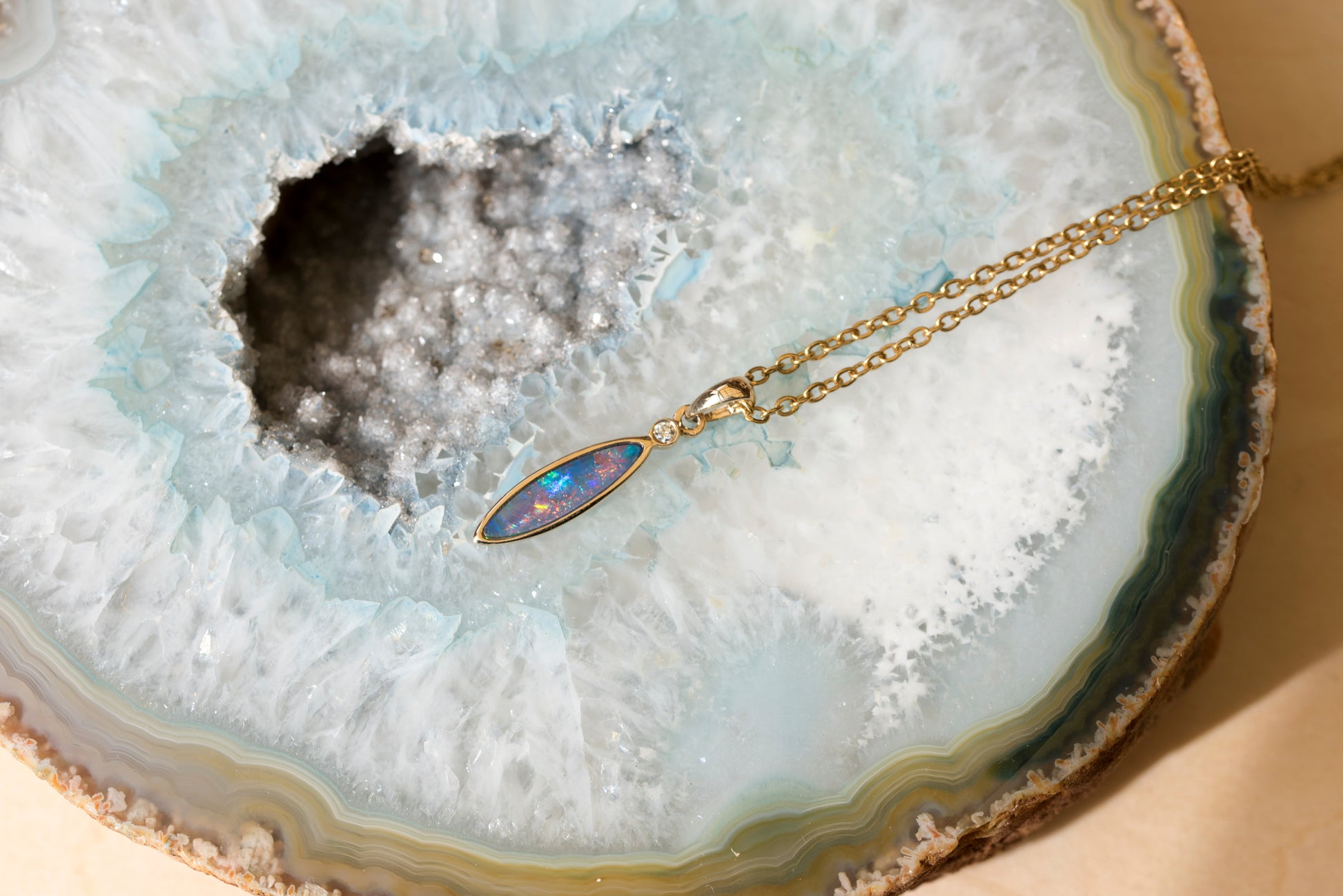 Gold opal necklace with a pendant on a geode