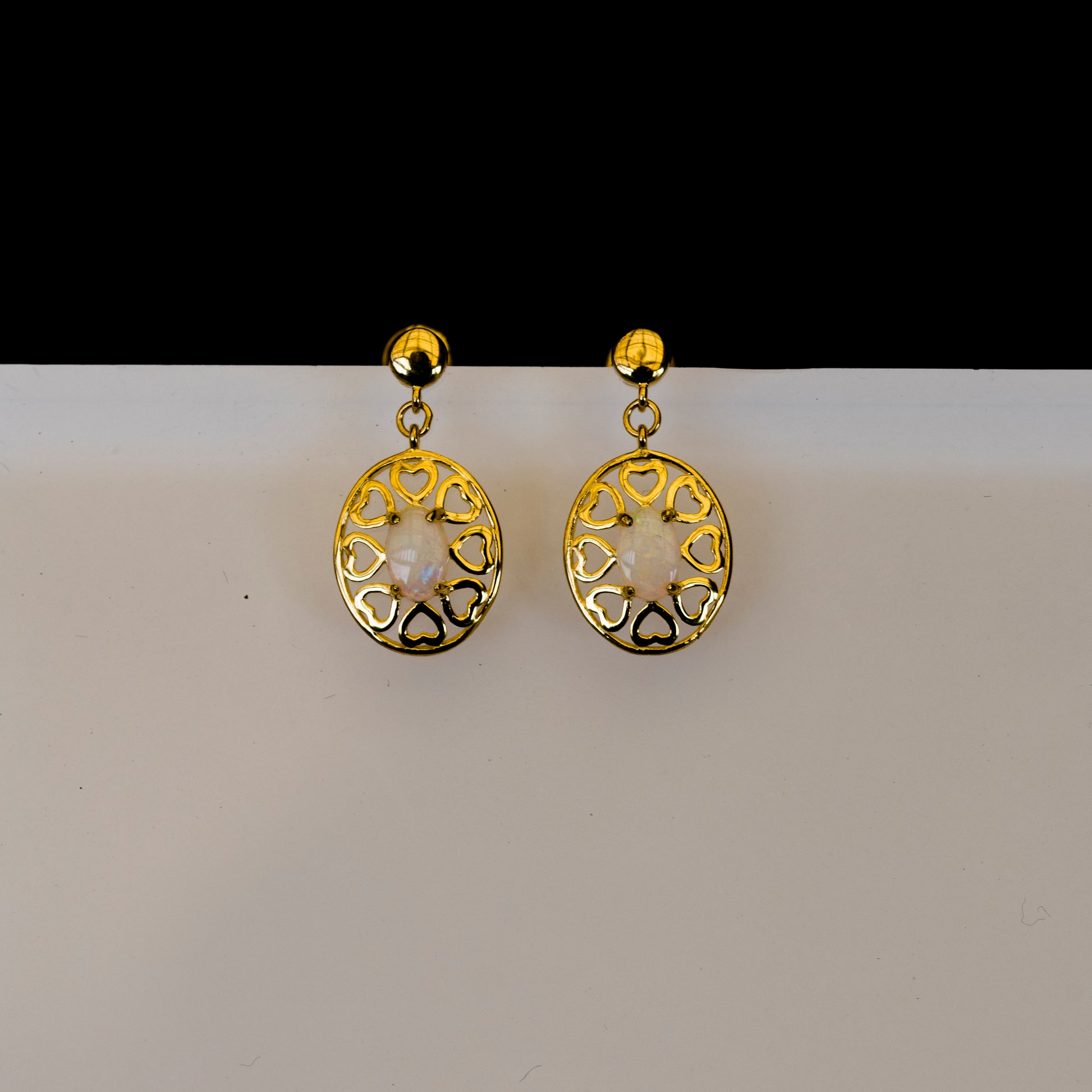 Gold earrings with intricate designs on a white background