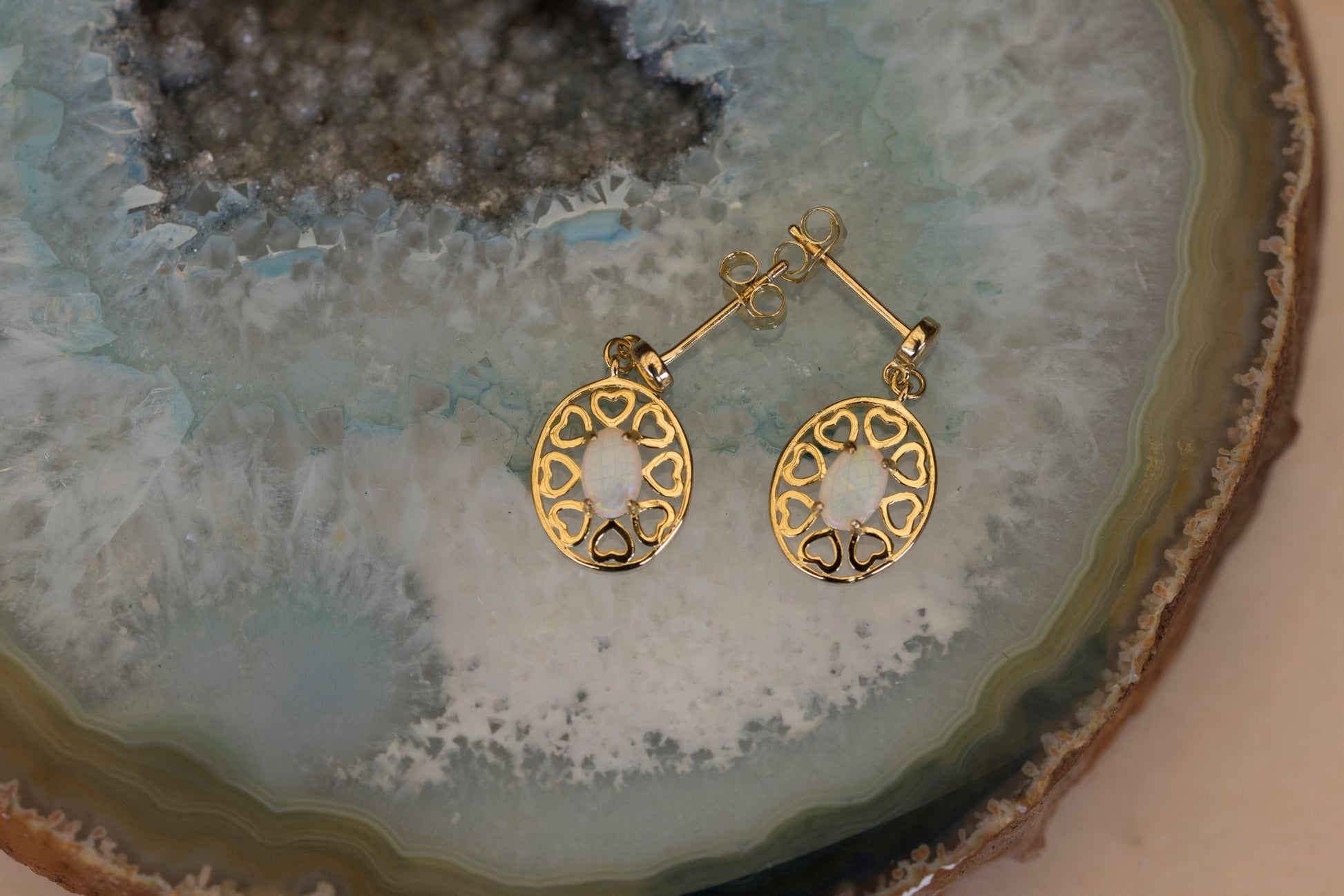Gold earrings on a textured stone surface