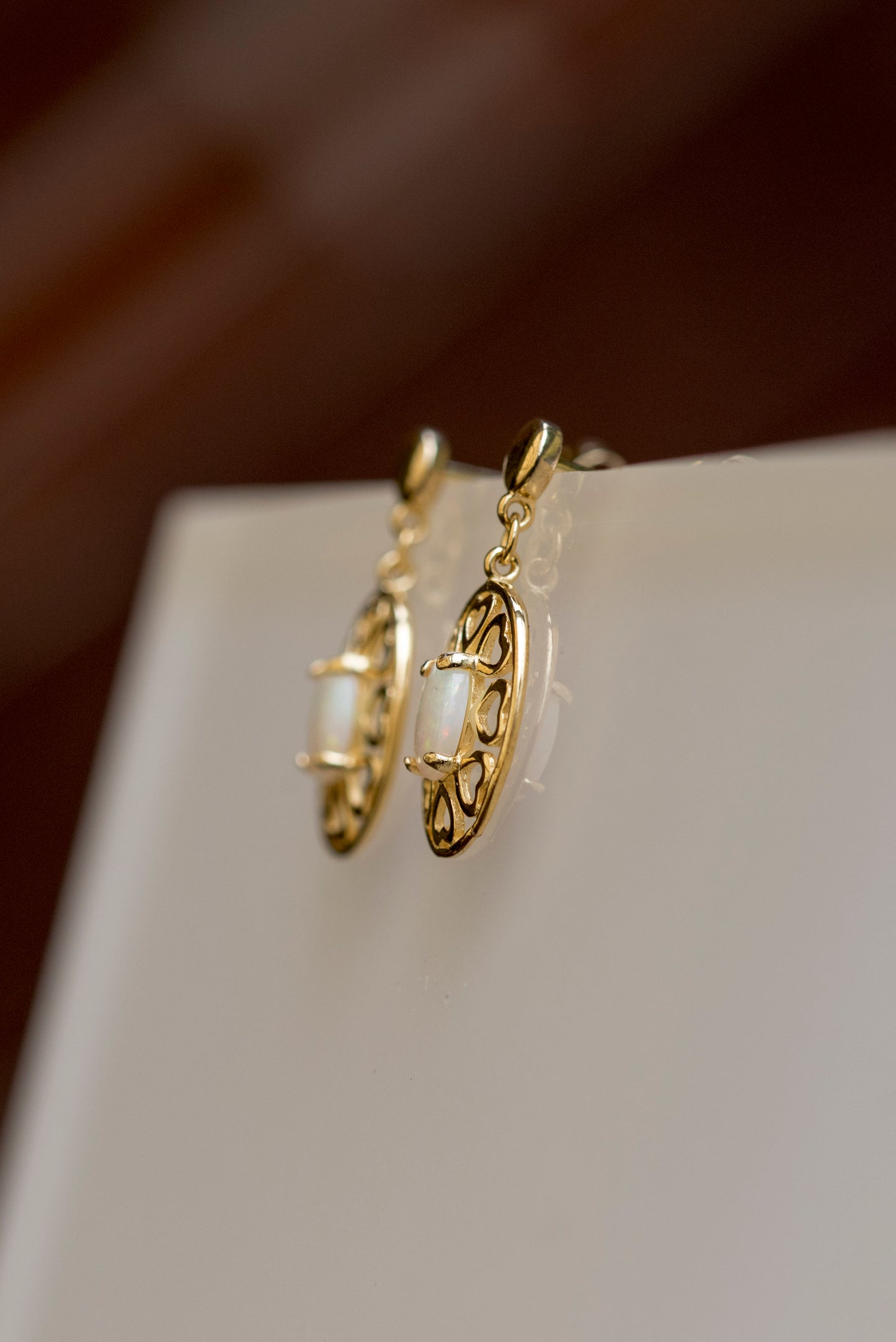 Gold earrings on a white surface with a blurred background