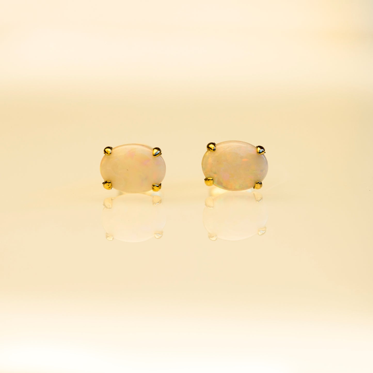 Pair of gold earrings with beige stones on a beige background