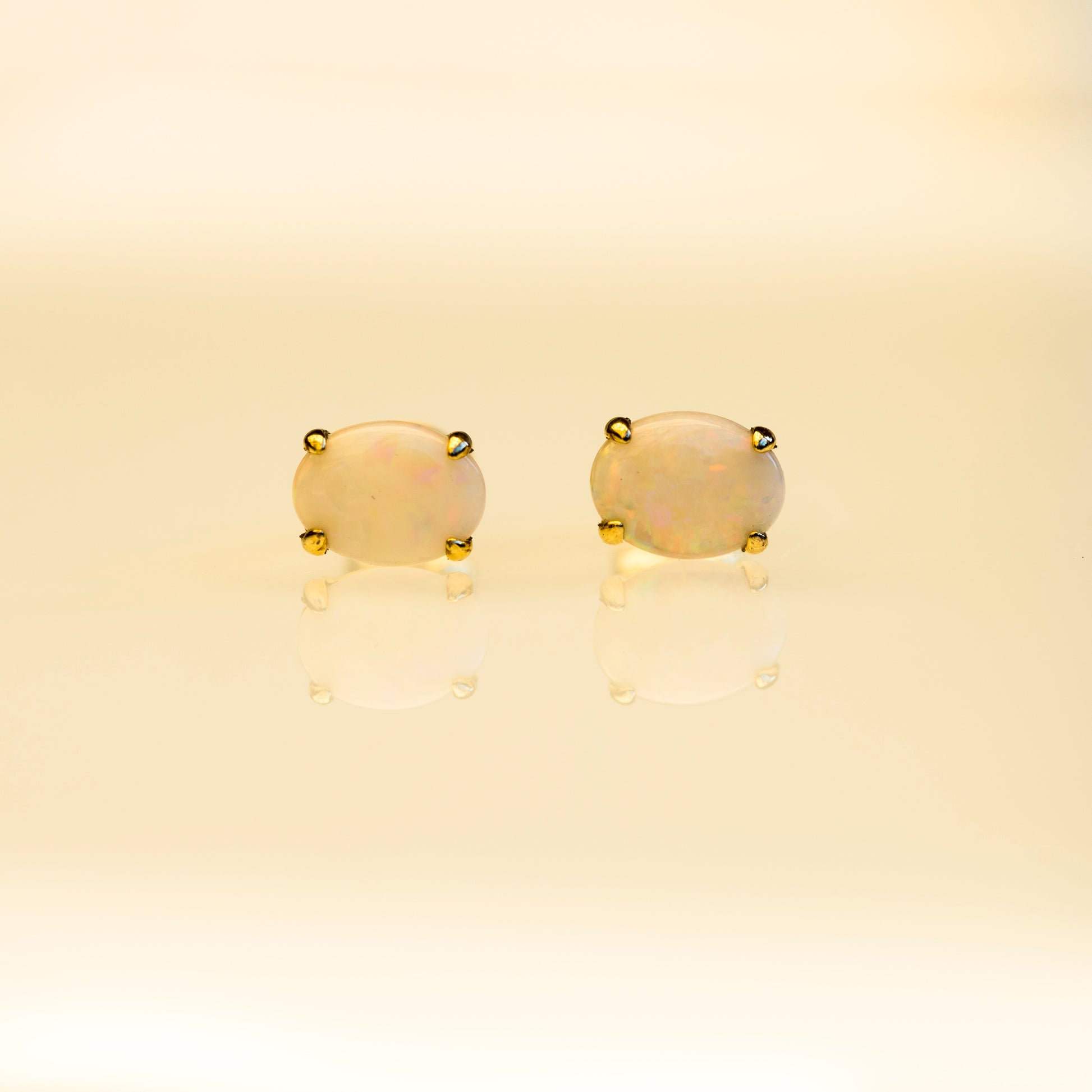 Pair of gold earrings with beige stones on a beige background