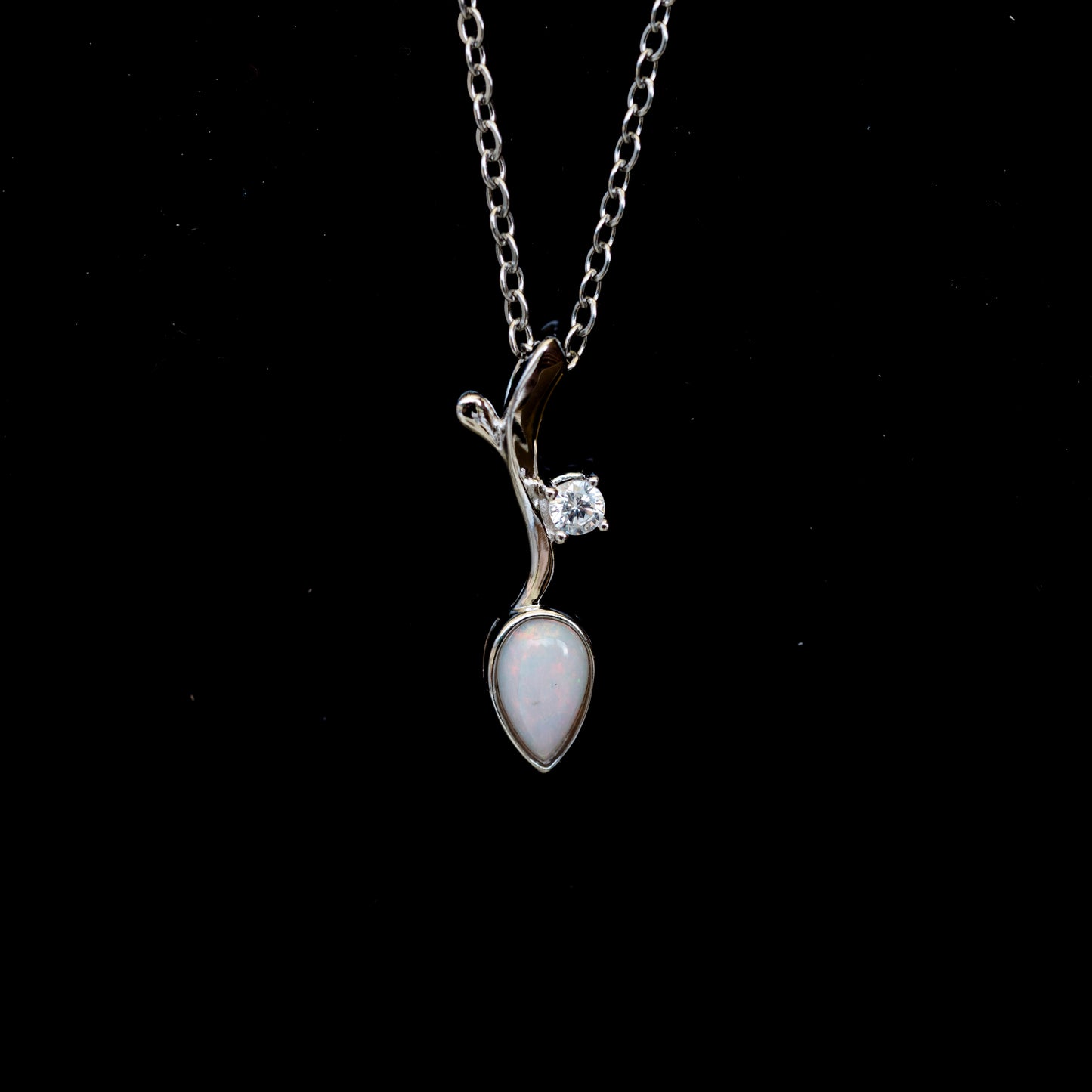 Silver necklace with a pendant featuring a teardrop-shaped opal gemstone on a black background