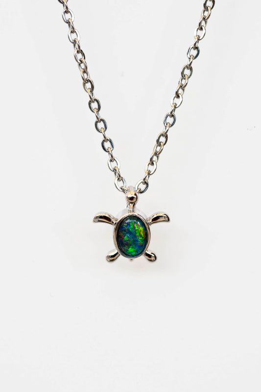 Turtle-shaped pendant necklace with a multicolored opal stone on a white background
